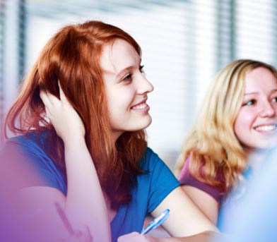 Two girsl sitting at a desk smiling