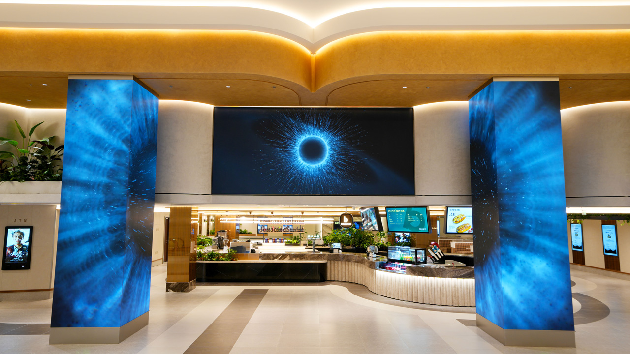 A spacious cinema lobby featuring a large LED screen and video walls, creating an inviting atmosphere for visitors.