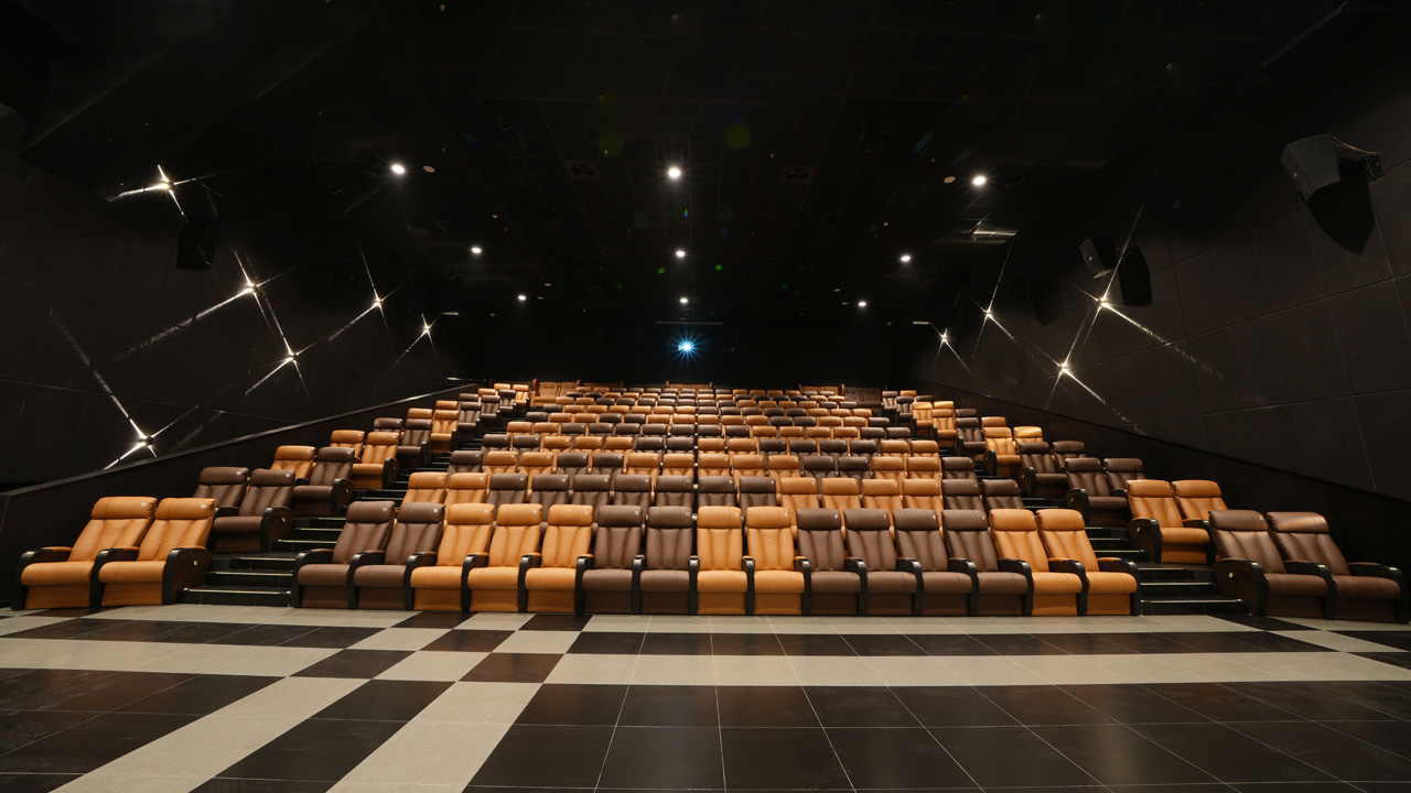 The interior of a high-end cinema auditorium featuring rows of seats in shades of brown, creating a dramatic and elegant atmosphere.