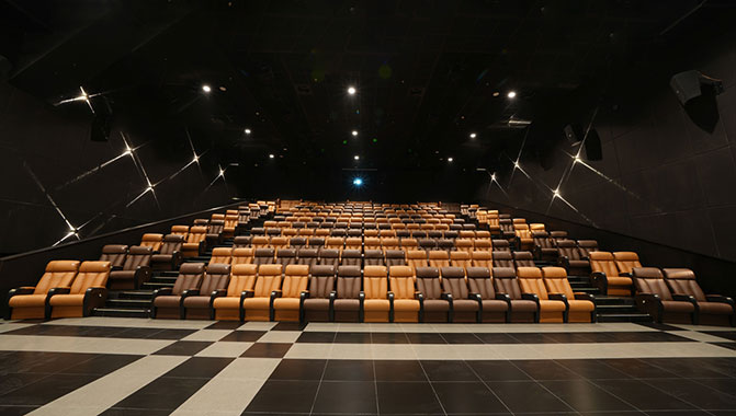The interior of a high-end cinema auditorium featuring rows of seats in shades of brown, creating a dramatic and elegant atmosphere.