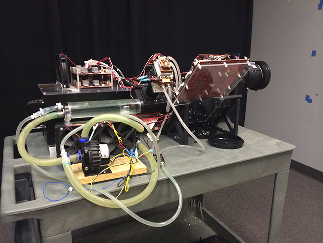 a prototype of a projector sitting on a table with wires and tubes protruding. 