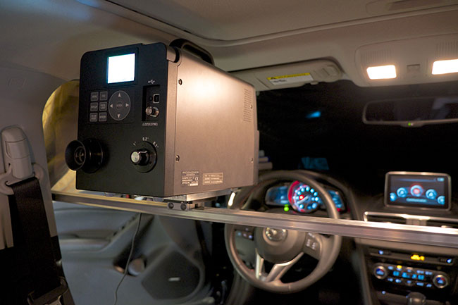 A black electronic box is mounted at eye-level in the driver&rsquo;s seat of a car.
