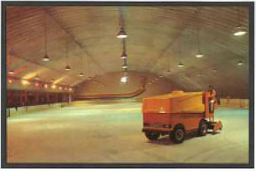 An orange Zamboni on an indoor ice rink. 
