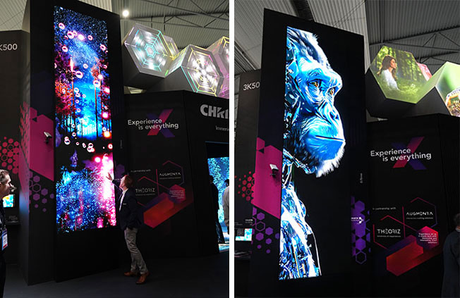 A man touches a tall LED video wall that has an image of a forest and bubbles displayed on it.