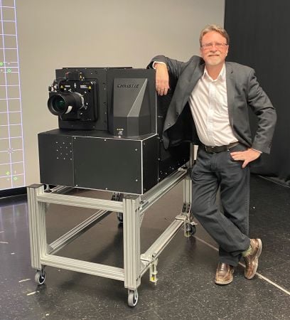 Man rests arm on the side of a Christie E3LH Dolby Vision Cinema Projection System.