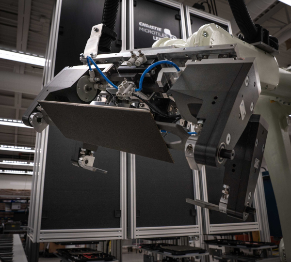 An LED tile is lifted by a robotic arm.