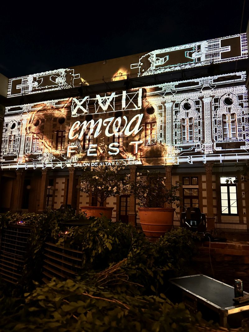 An elaborate indoor fa&ccedil;ade is surrounded by plants and projection mapped with an intricate black and white design.
