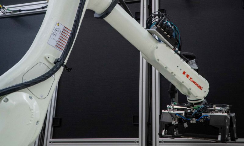 A robotic arm in front of a black wall.