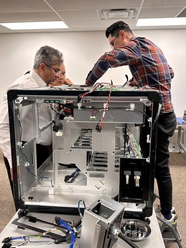A small group of people repair a large projector. 