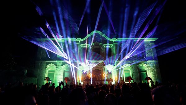 A crowd in front of a brightly illuminated building outside at night.