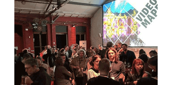 Three men standing together in front of a table and Pandoras Box advertising